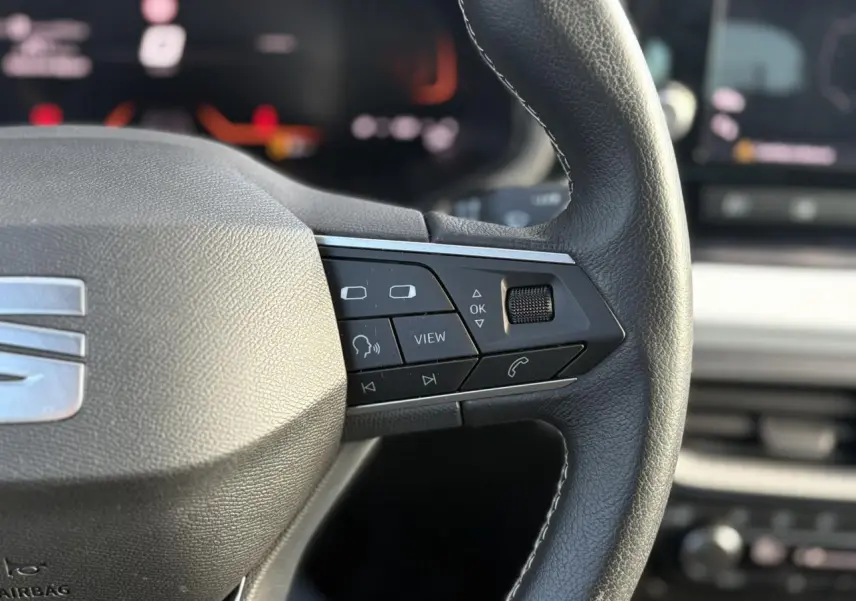 Gros plan sur le volant cuir multifonction droit du SEAT Arona gris avec commandes audio et appel intégrées.