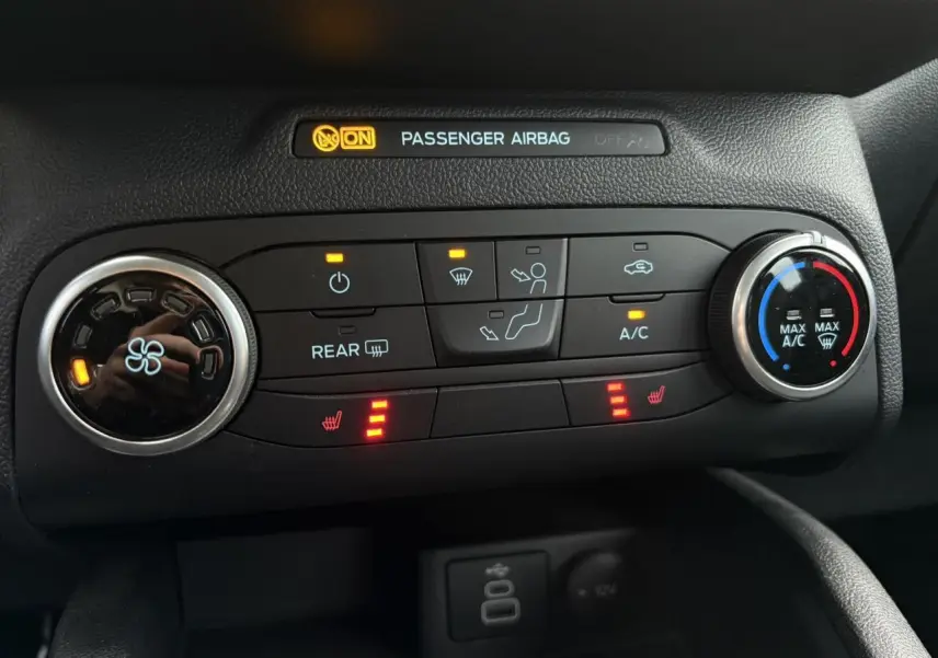 Gros plan sur la console de climatisation du Ford Kuga 2024 noir Obsidien avec commandes chauffantes et ventilation active.