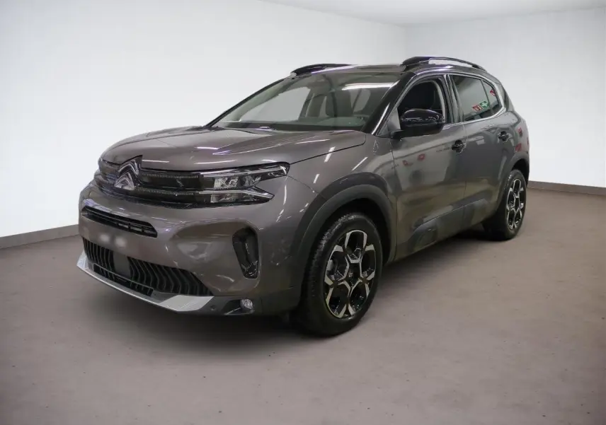 Citroën C5 Aircross Hybrid gris Platinium en 3/4 avant droit, avec jantes bi-ton et barres de toit noires.