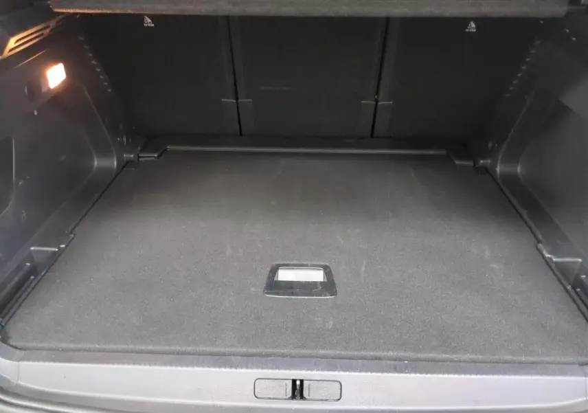Coffre ouvert vu de face d’un Citroën C5 Aircross Hybrid gris Platinium avec hayon électrique et éclairage intérieur.