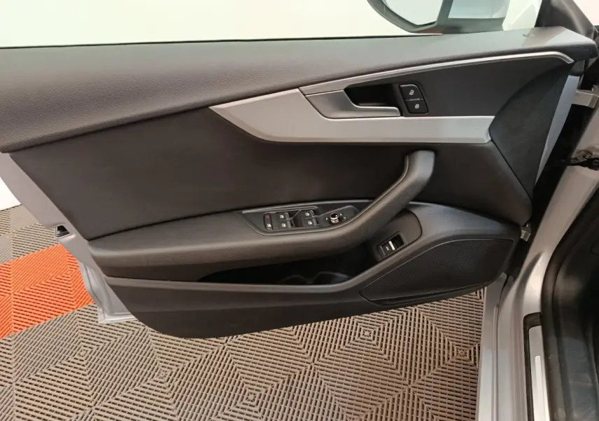 Vue intérieure sur la porte avant gauche gris clair de l'Audi A5 40 TFSI avec commandes de vitres et verrouillage.