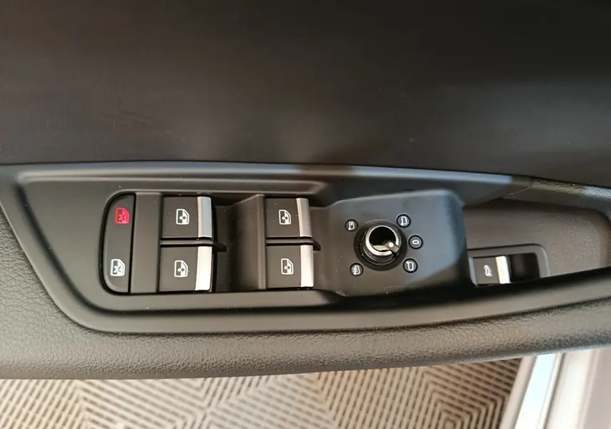 Gros plan sur les commandes de lève-vitres et rétroviseurs côté conducteur d'une Audi A5 gris clair de 2019.