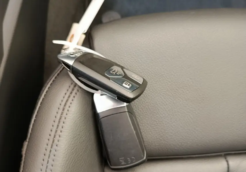 Gros plan sur la clé Audi posée sur un siège en cuir gris clair à l'intérieur du véhicule.