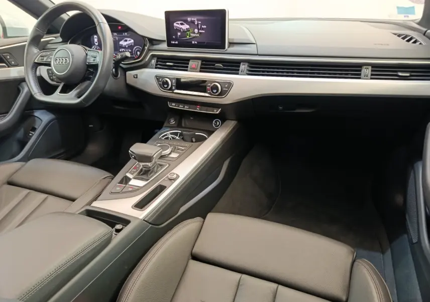 Vue intérieure côté conducteur de l'Audi A5 40 TFSI 2019, tableau de bord moderne avec écran central et volant cuir multifonctions.