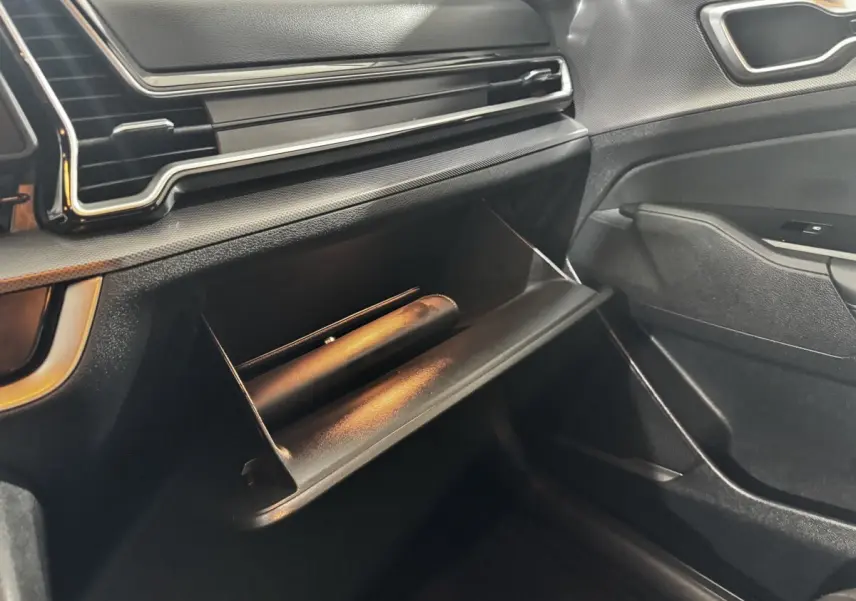 Vue intérieure côté passager du coffre à gants ouvert du Kia Sportage blanc 2024 avec tableau de bord noir.