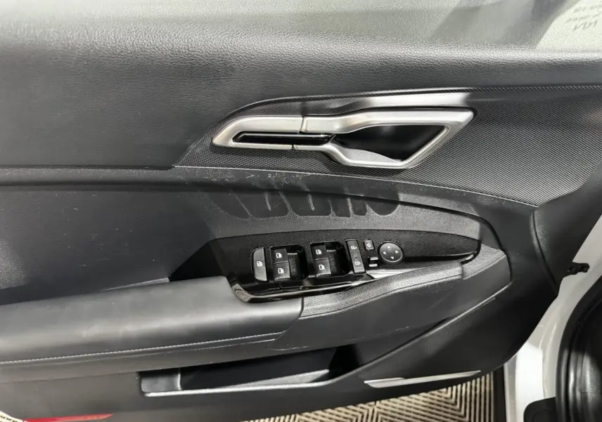 Vue rapprochée de la porte avant gauche blanche du Kia Sportage 2024, avec commandes électriques et poignée argentée.