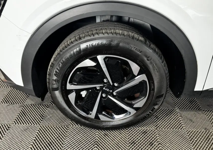 Gros plan sur la roue avant droite du KIA SPORTAGE blanc 2024 avec jante alliage noire et argentée Michelin.