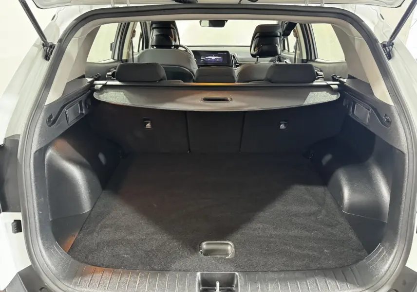 Coffre ouvert d’un KIA Sportage blanc 2024, vue arrière montrant l’espace de chargement et la tablette cache-bagages.