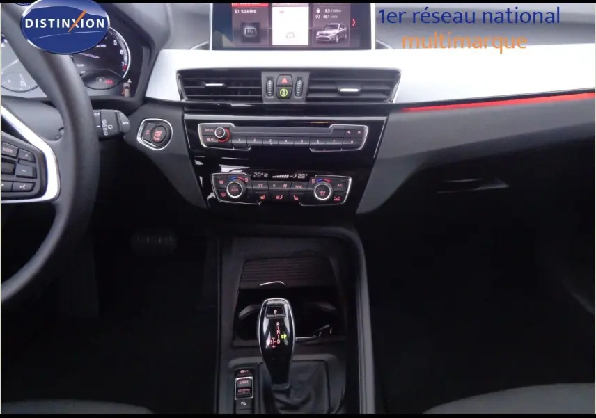 Intérieur noir du BMW X1 2022, vue centrée sur la console centrale avec levier de vitesse automatique et tableau de bord digital.