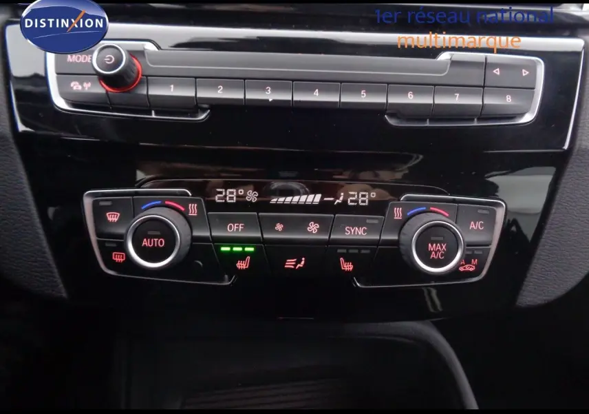 Tableau de bord du BMW X1 blanc Alpine Metal 2022 montrant les commandes de climatisation automatique et chauffage des sièges.