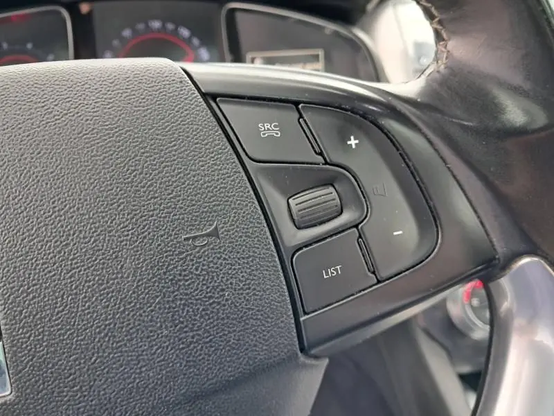 Gros plan sur les commandes audio au volant en cuir noir du Citroën DS5 gris foncé métal de 2014.