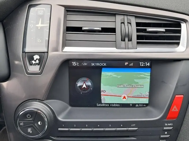 Tableau de bord de Citroën DS5 gris foncé, affichage GPS et horloge analogique avec bouton start/stop visible.