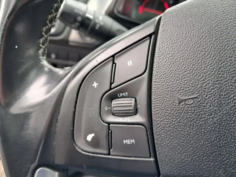 Gros plan sur les commandes du volant d'une Citroën DS5 gris foncé métal, mettant en valeur les boutons de régulateur de vitesse.