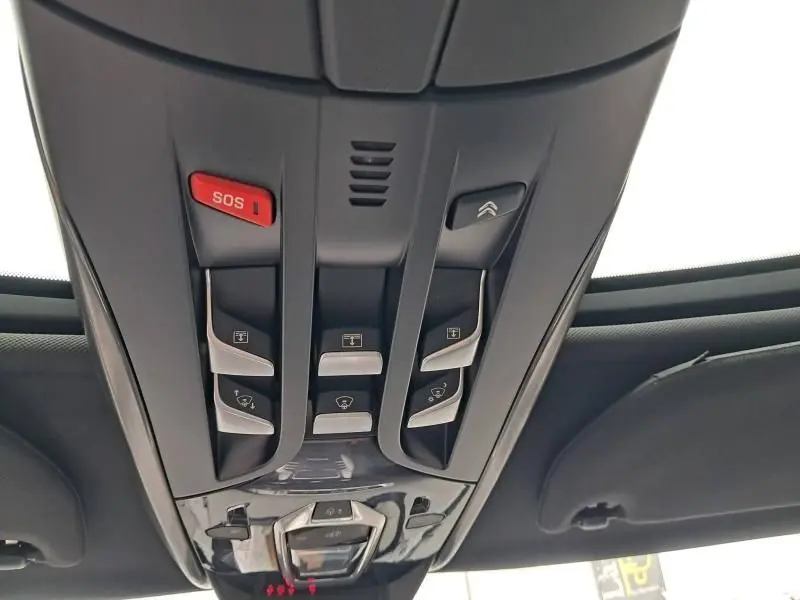 Vue en contre-plongée du panneau de commandes de toit noir du Citroën DS5 gris foncé, avec bouton SOS rouge bien visible.