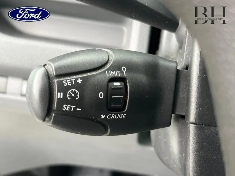 Gros plan sur la commande de régulateur de vitesse noire dans l'habitacle du Peugeot Expert Fourgon blanc Banquise.