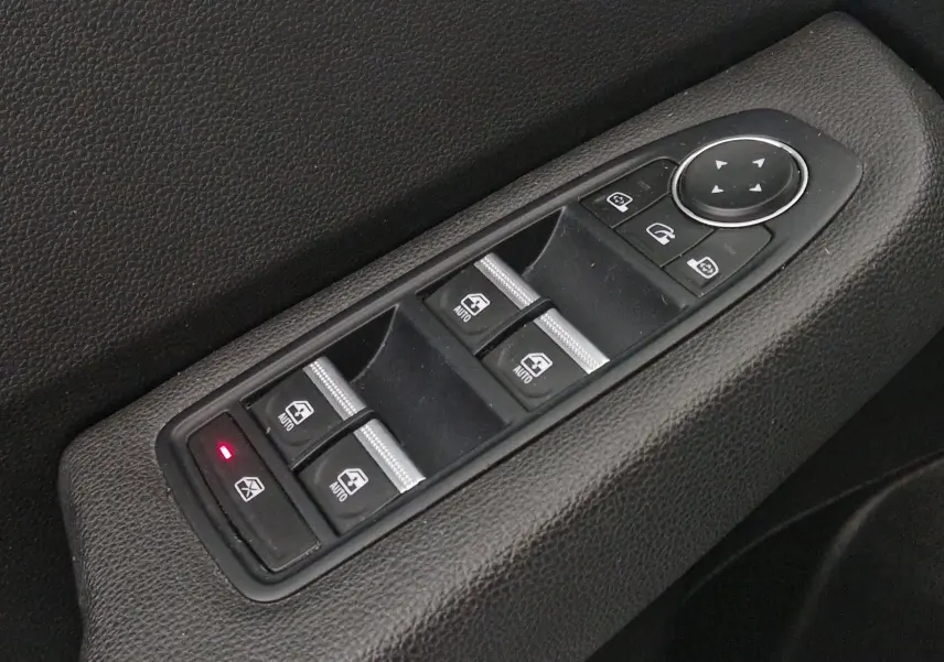 Gros plan sur les commandes électriques des vitres et rétroviseurs côté conducteur de la Renault Clio V gris platine 2021.