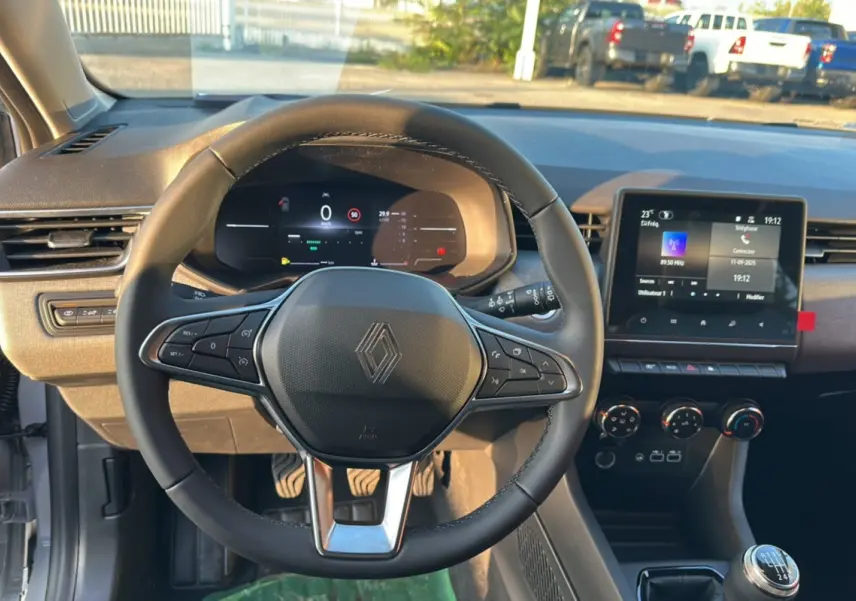 Vue intérieure centrée sur le volant de la Renault Clio DCI 100 Evolution Camera 2025 en gris rafale, avec tableau de bord numérique et écran tactile.