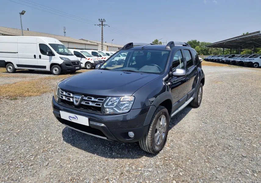 Dacia Duster 1.5 DCI 110 Prestige gris foncé métal vue 3/4 avant droit sur terrain gravillonné.