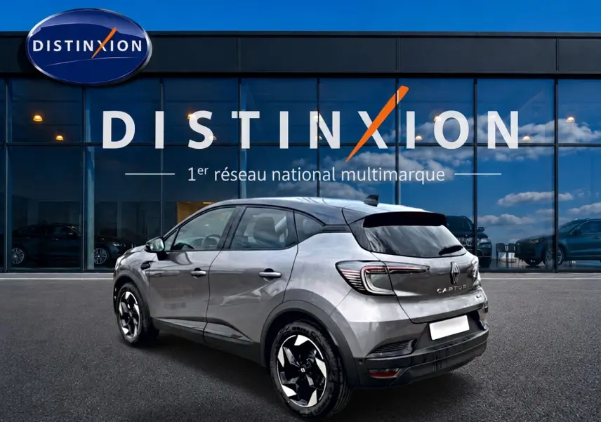 Renault Captur 1.8 e-tech hybride 2026 gris Cassiope toit noir, vue 3/4 arrière côté gauche, jantes alu distinctives.