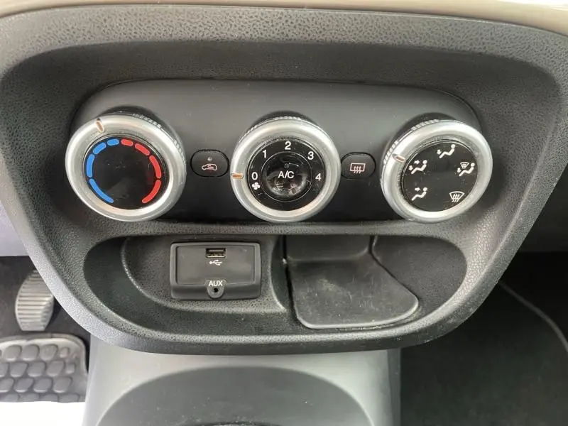 Gros plan sur les commandes de climatisation et prise USB d'une Fiat 500L beige de 2014, version Tekking diesel.