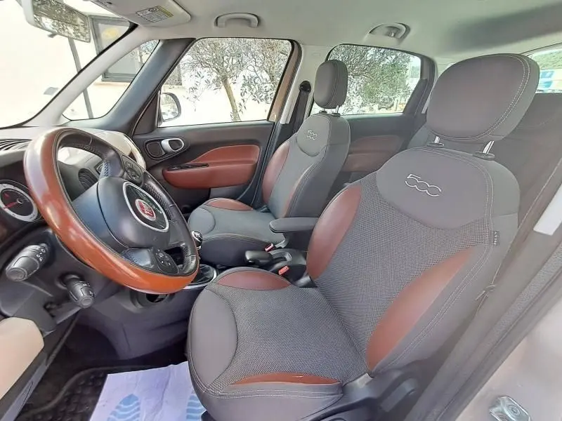Vue intérieure côté conducteur de la Fiat 500L beige 2014, sièges gris et marron avec logo 500 brodé, volant bi-ton bois et cuir.