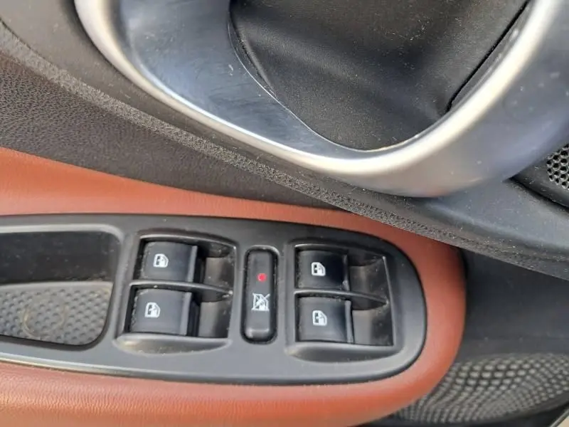 Gros plan sur les commandes des vitres électriques côté conducteur d'une Fiat 500L beige avec garniture intérieure marron.