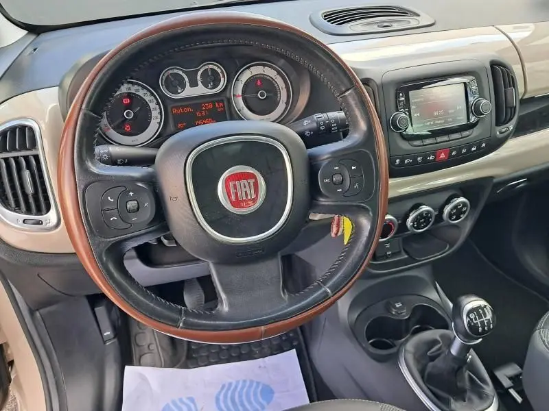 Intérieur beige de la Fiat 500L 2014, vue sur le volant cuir, tableau de bord et levier de vitesse manuel.