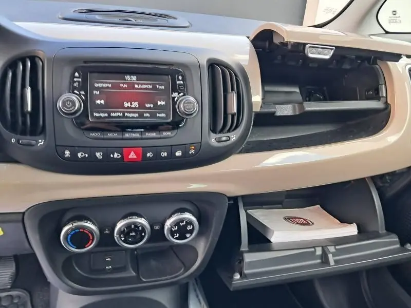Tableau de bord beige de la Fiat 500L 2014, version Tekking, avec console centrale et boîte à gants ouverte.