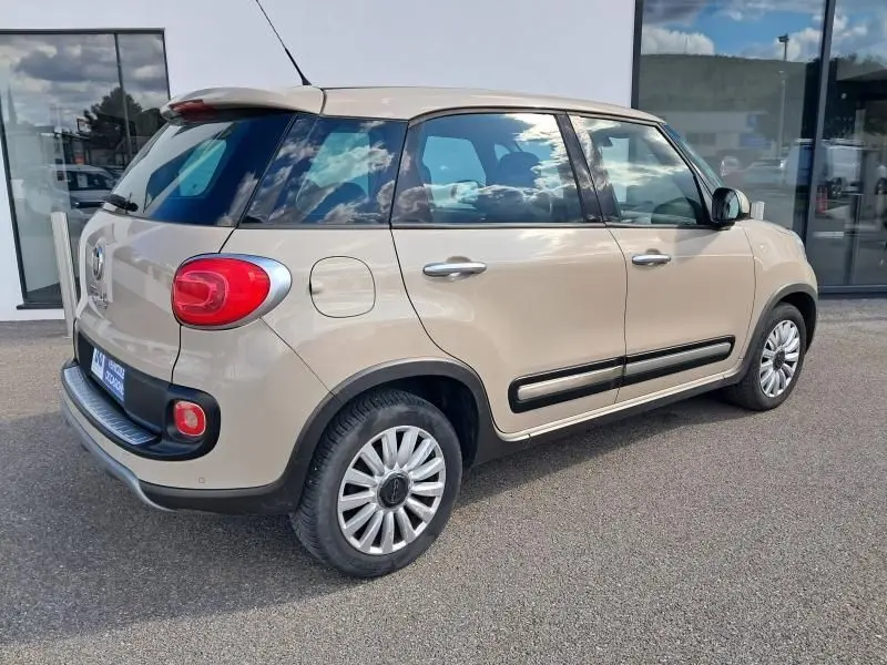 Fiat 500L beige vue 3/4 arrière droit, avec feux arrière ronds et protections latérales noires.