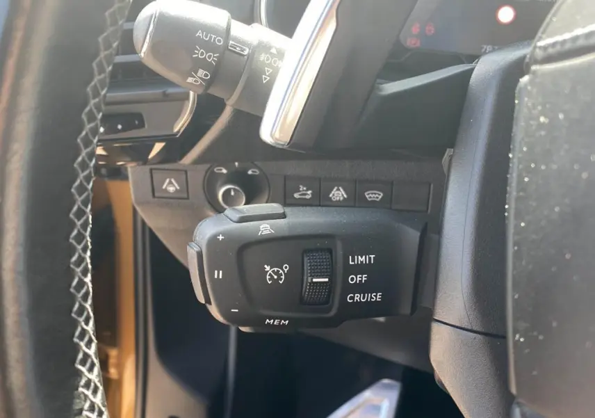 Gros plan sur la commande de régulateur de vitesse à gauche du volant d’un DS7 Crossback jaune clair 2018.