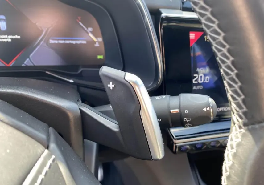 Gros plan sur la palette de changement de vitesse + du DS7 Crossback jaune clair, avec tableau de bord numérique en arrière-plan.