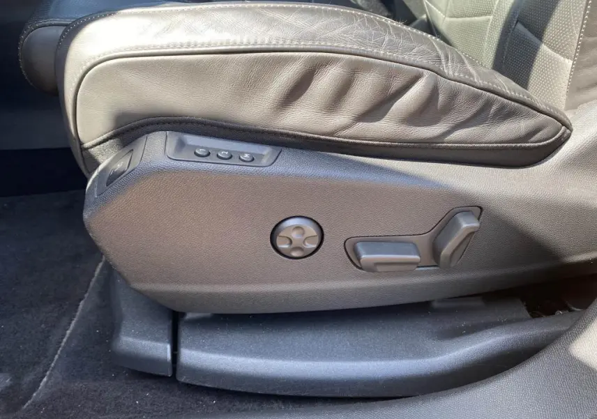 Gros plan sur les commandes de réglage électrique du siège avant en cuir noir du DS7 Crossback jaune clair.