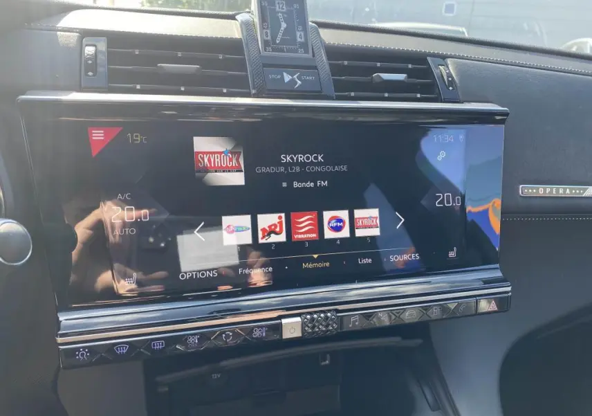Tableau de bord du DS7 Crossback OPERA avec écran tactile central affichant la radio Skyrock et horloge analogique.