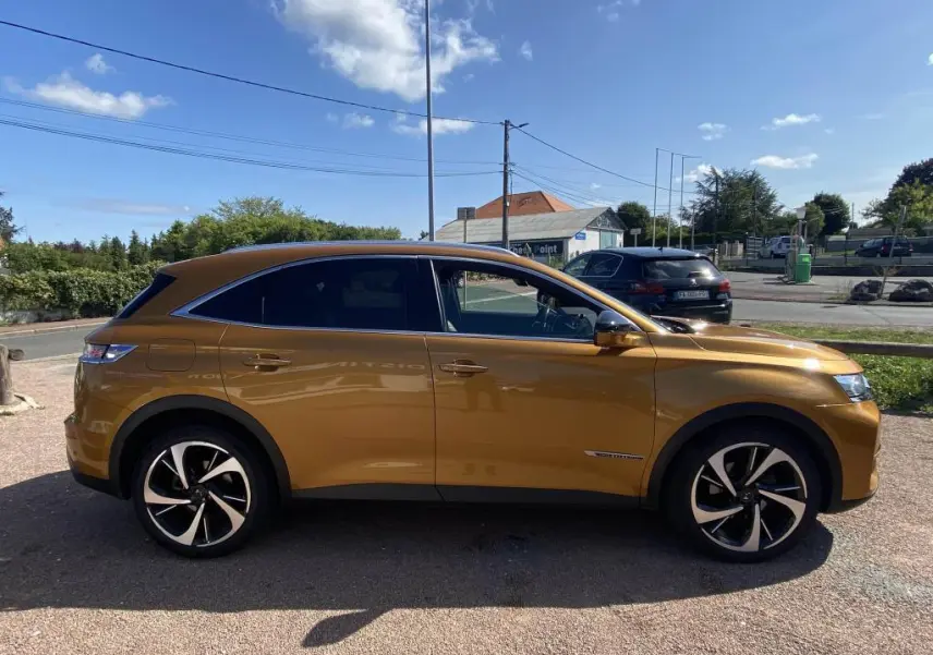 Vue latérale droite d'un DS7 Crossback jaune clair avec jantes noires et chromées, stationné en extérieur.