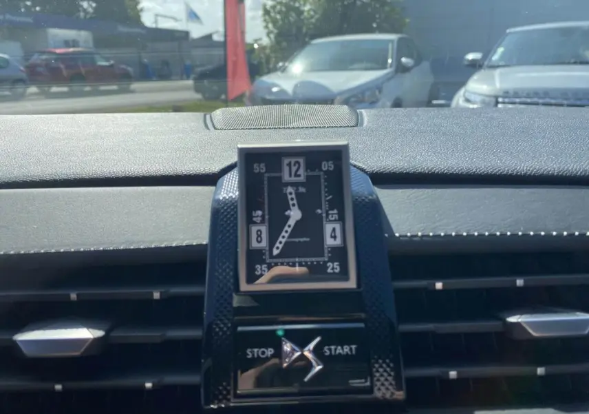 Gros plan sur l'horloge analogique centrale et le bouton stop/start du tableau de bord du DS7 Crossback, intérieur noir.
