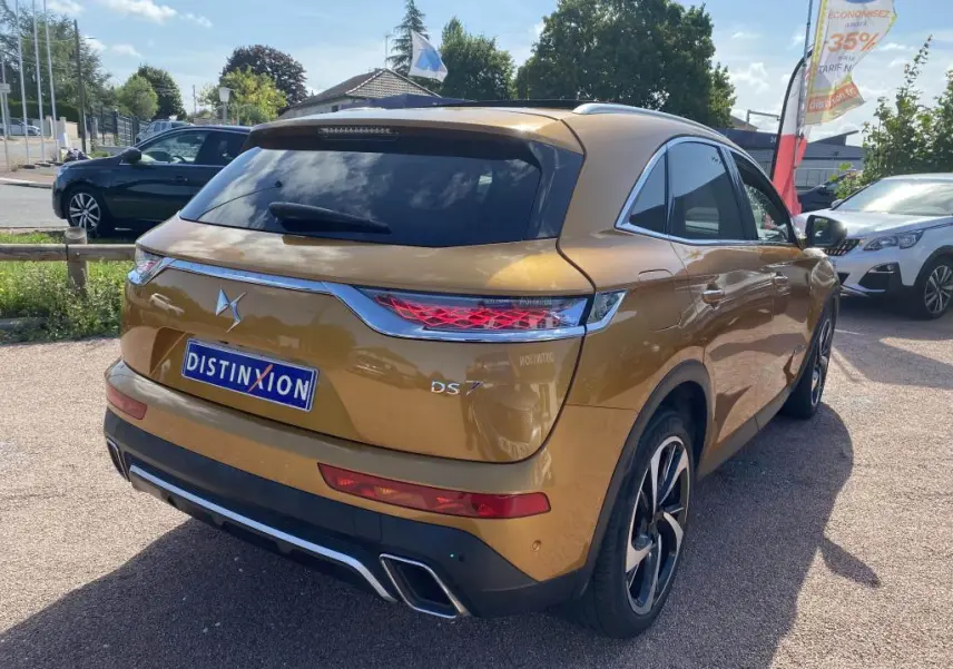 Vue 3/4 arrière droite d'un DS7 Crossback jaune clair avec feux arrière LED et double sortie d'échappement chromée.