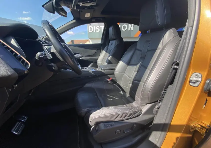 Vue intérieure côté conducteur du DS7 Crossback jaune clair, sièges cuir noir et toit ouvrant panoramique visible