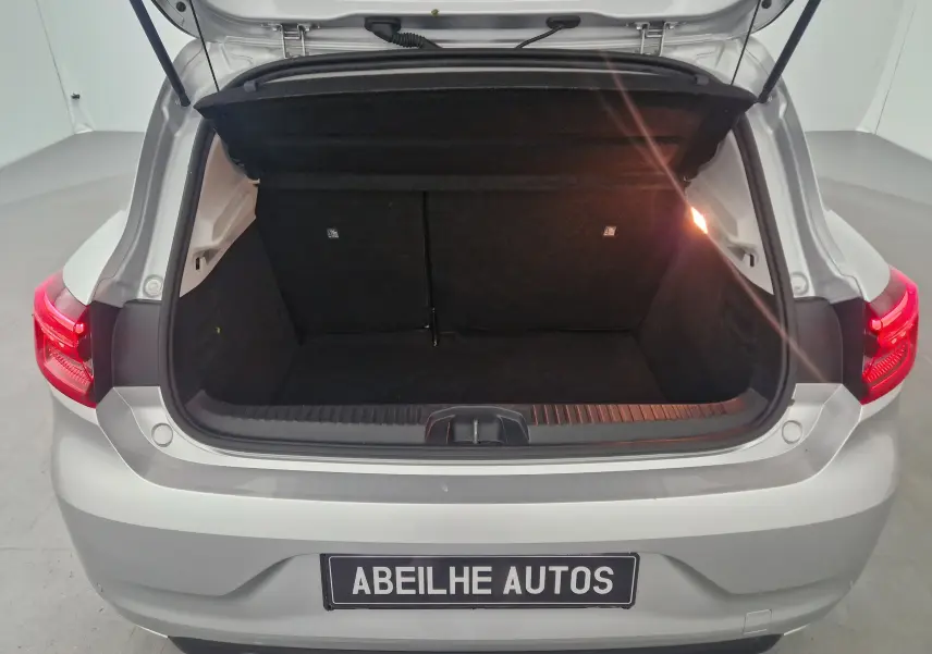 Coffre ouvert vu de l'arrière d'une Renault Clio V gris platine, avec feux arrière allumés et plaque Abeilhe Autos.
