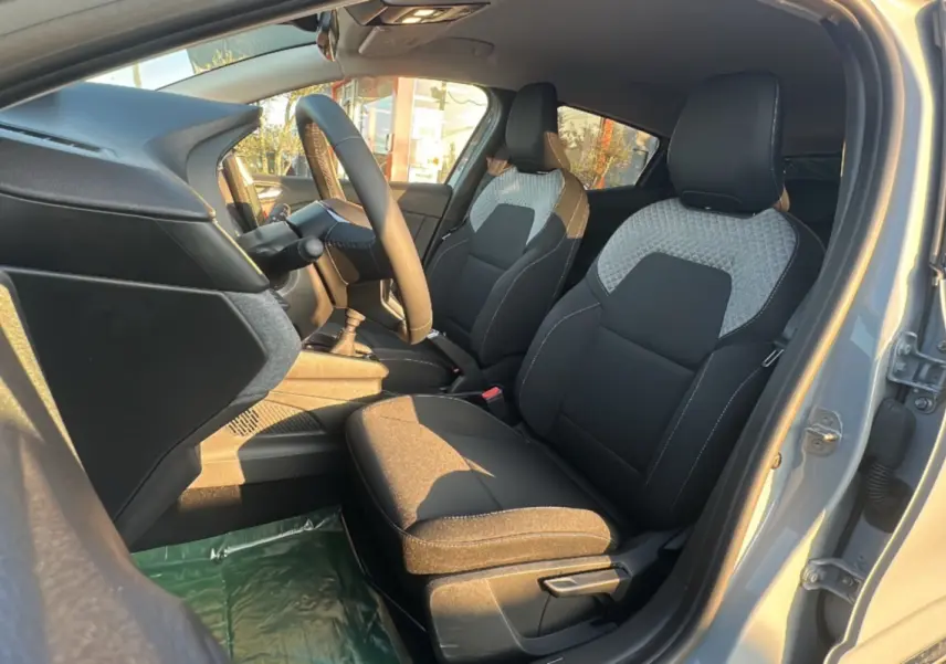 Intérieur avant droit de la Renault Clio 2025 gris rafale, sièges tissu bicolore avec motifs géométriques.