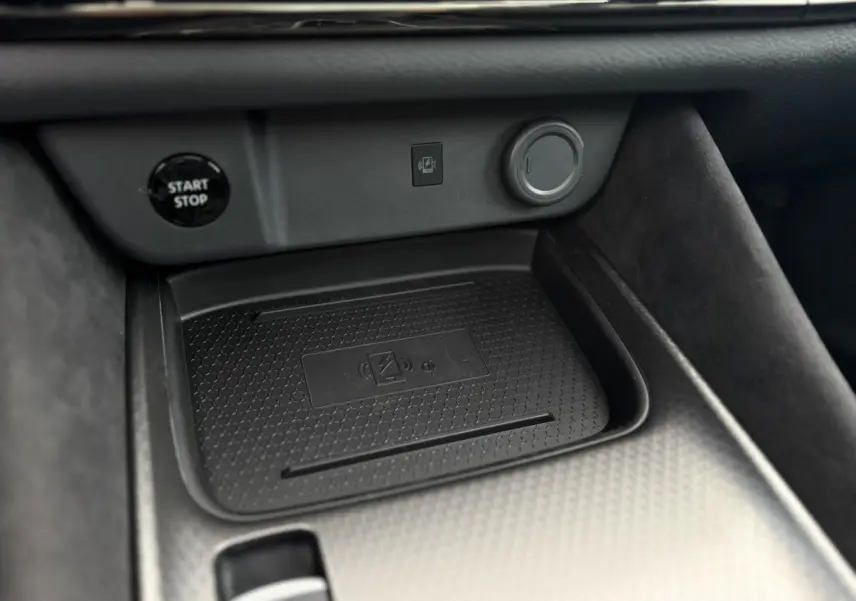 Gros plan sur la console centrale du Nissan Qashqai gris Ceramic, mettant en valeur le chargeur à induction et le bouton Start/Stop.