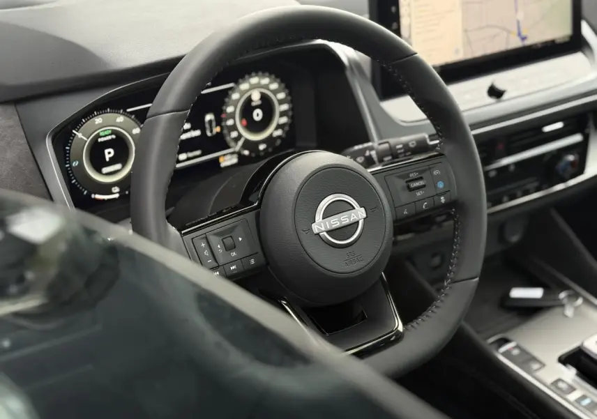 Vue rapprochée du volant cuir noir du Nissan Qashqai 2025 avec tableau de bord numérique et écran tactile GPS.