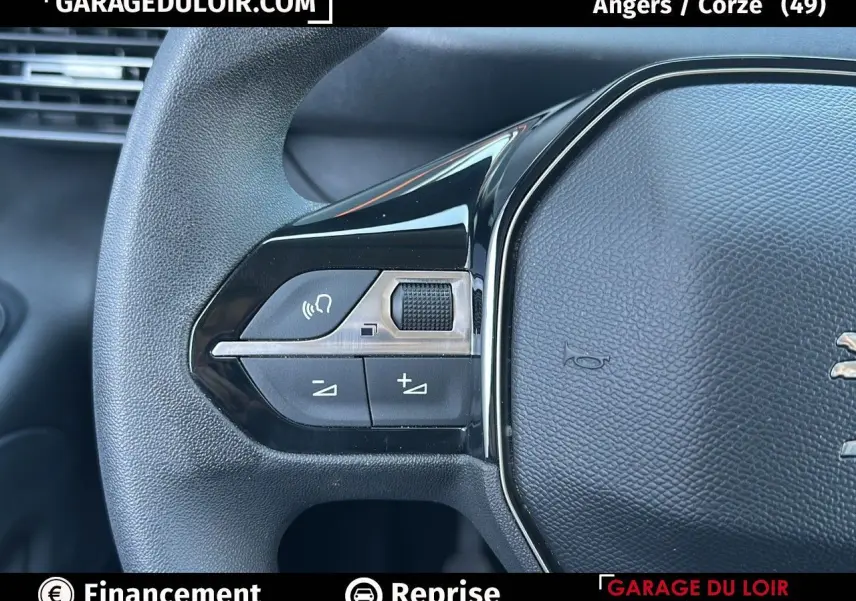 Gros plan sur le volant cuir multifonction noir du Peugeot Rifter bleu avec commandes intégrées à gauche.