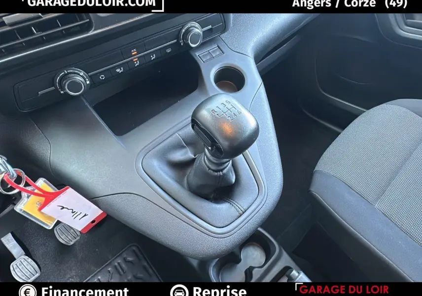 Gros plan sur la console centrale et levier de vitesses manuelle du Peugeot Rifter bleu, sièges tissu gris visibles.