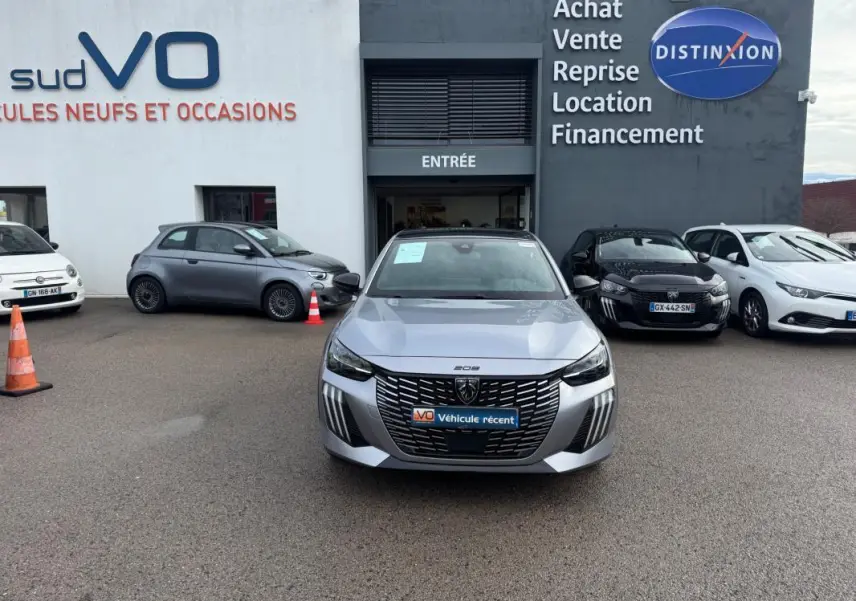 Peugeot 208 Hybrid gris vue de face, avec calandre noire distinctive et feux diurnes verticaux allumés.