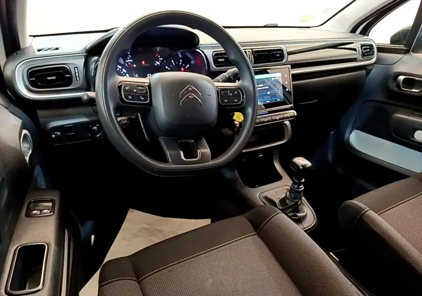 Vue intérieure avant de la Citroën C3 2022 avec volant multifonctions, tableau de bord noir et levier de vitesse manuel.