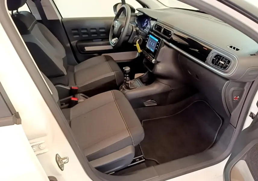 Intérieur côté conducteur d'une Citroën C3 blanche 2022, montrant sièges noirs et tableau de bord avec écran tactile.