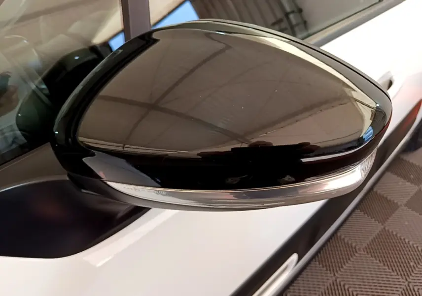 Gros plan sur le rétroviseur droit noir brillant avec clignotant intégré d'une Citroën C3 blanche vue de côté.