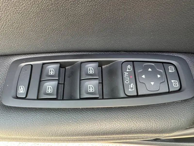 Gros plan sur les commandes des vitres électriques et rétroviseurs sur la porte côté gauche d'une Renault Mégane Break gris Titanium 2024.