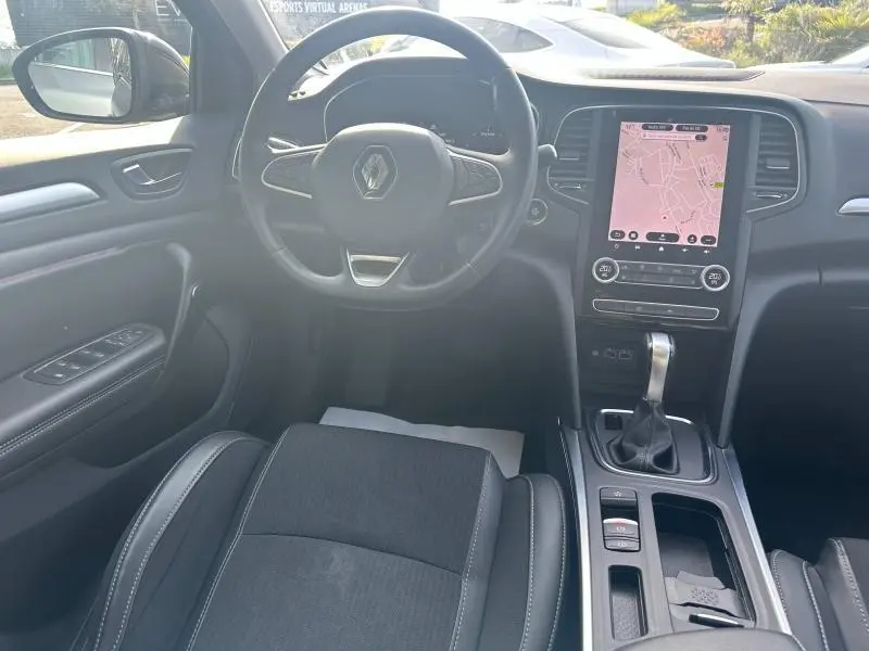 Vue intérieure avant de la Renault Mégane Break 2024, volant multifonction et écran tactile avec navigation visible.