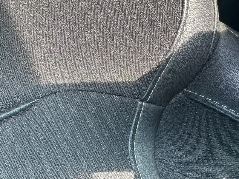 Gros plan sur le siège avant en tissu noir et similicuir avec surpiqûres blanches du Renault Mégane Break 2024.